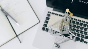 un laptop ed un carrello della spesa in miniatura che simboleggiano come vendere online